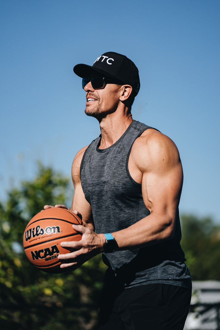 Man holding a basketball outdoors with a clear blue sky